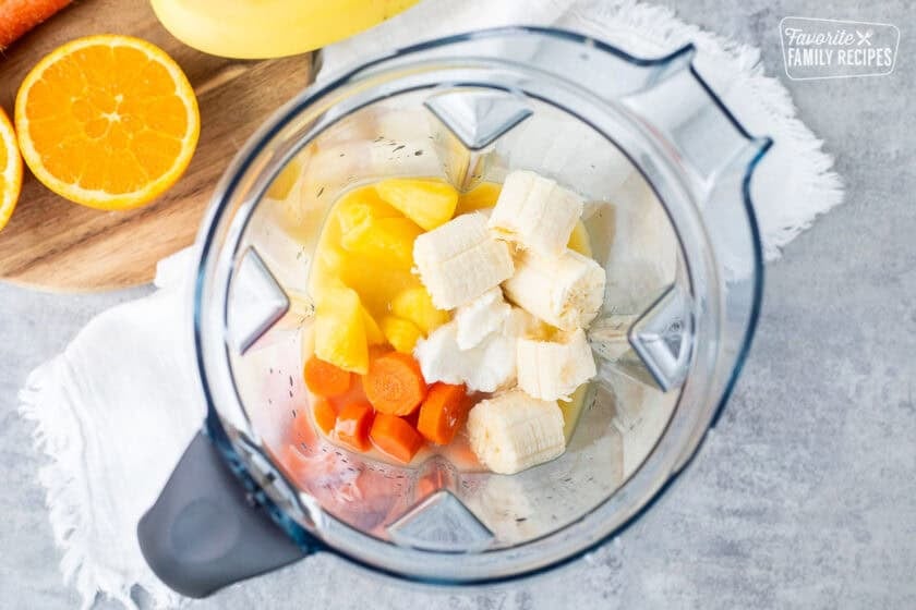 Blender with orange juice, pineapple, banana, honey greek yogurt and carrot.