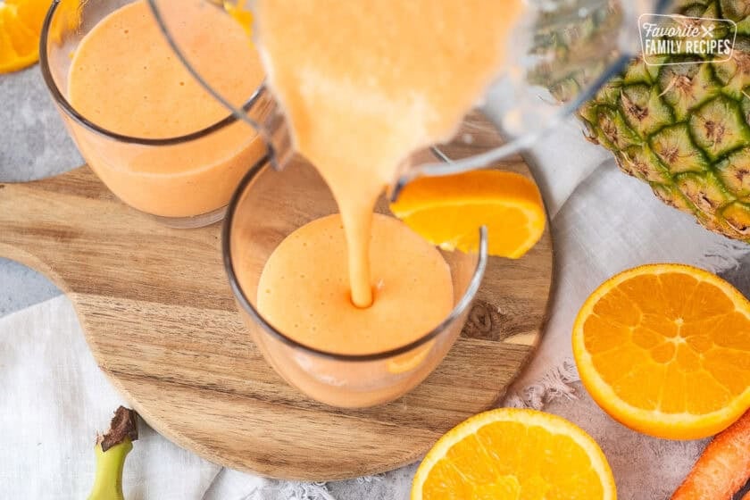 Pouring golden detox smoothie into a glass.