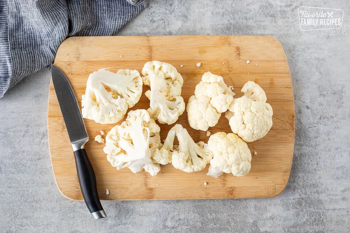 Cutting board with cut pieces of raw cauliflower.