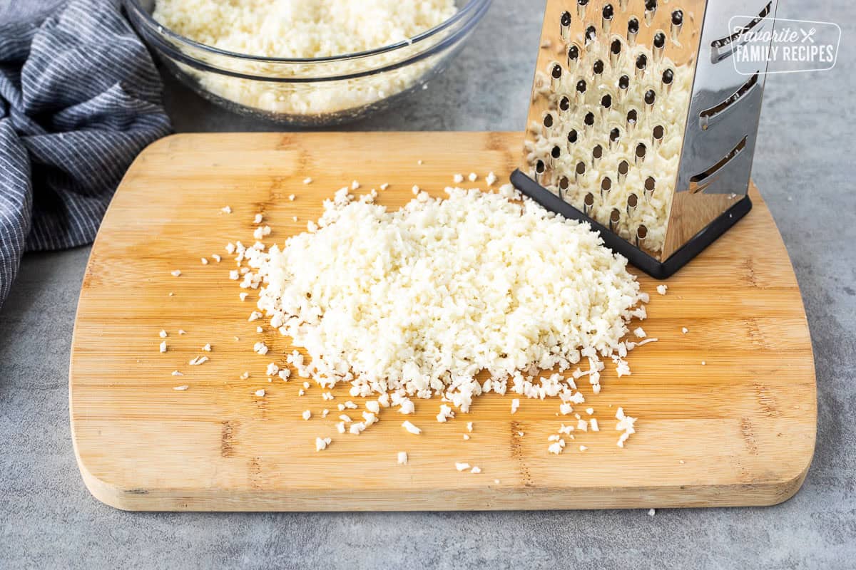 Grated cauliflower on a cutting board into rice size pieces.