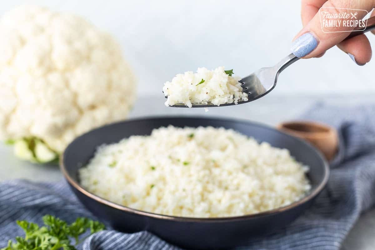 Fork with cauliflower rice over a bowl.
