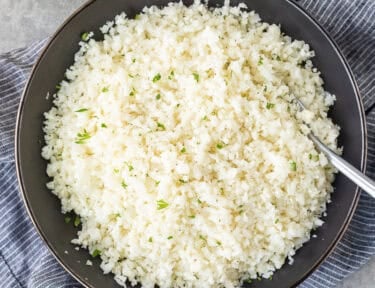 Bowl of cauliflower rice garnished with parsley.