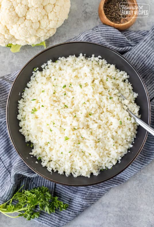 Bowl of cauliflower rice garnished with parsley.