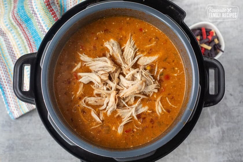 Shredded chicken in instant pot of enchilada soup.