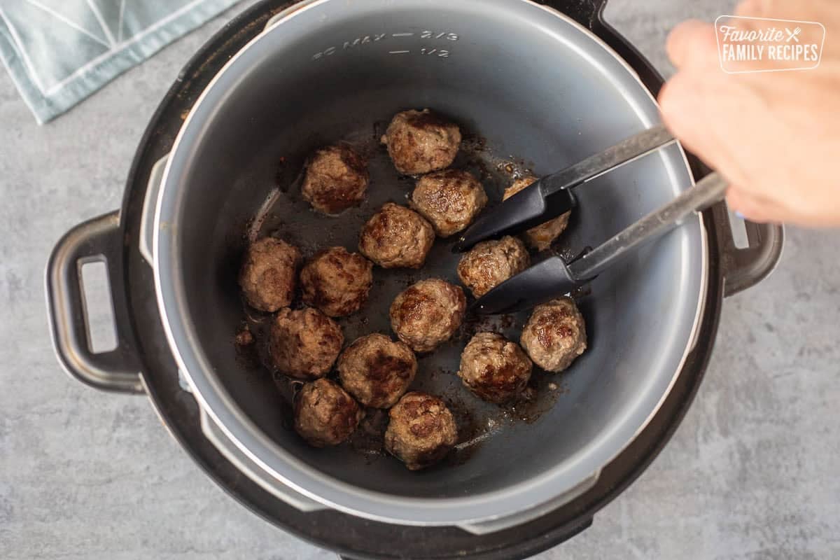 Sautéing Swedish meatballs in an instant pot and flipping with tongs.