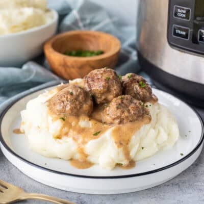 Plate of Swedish meatballs over mashed potatoes next to instant pot.