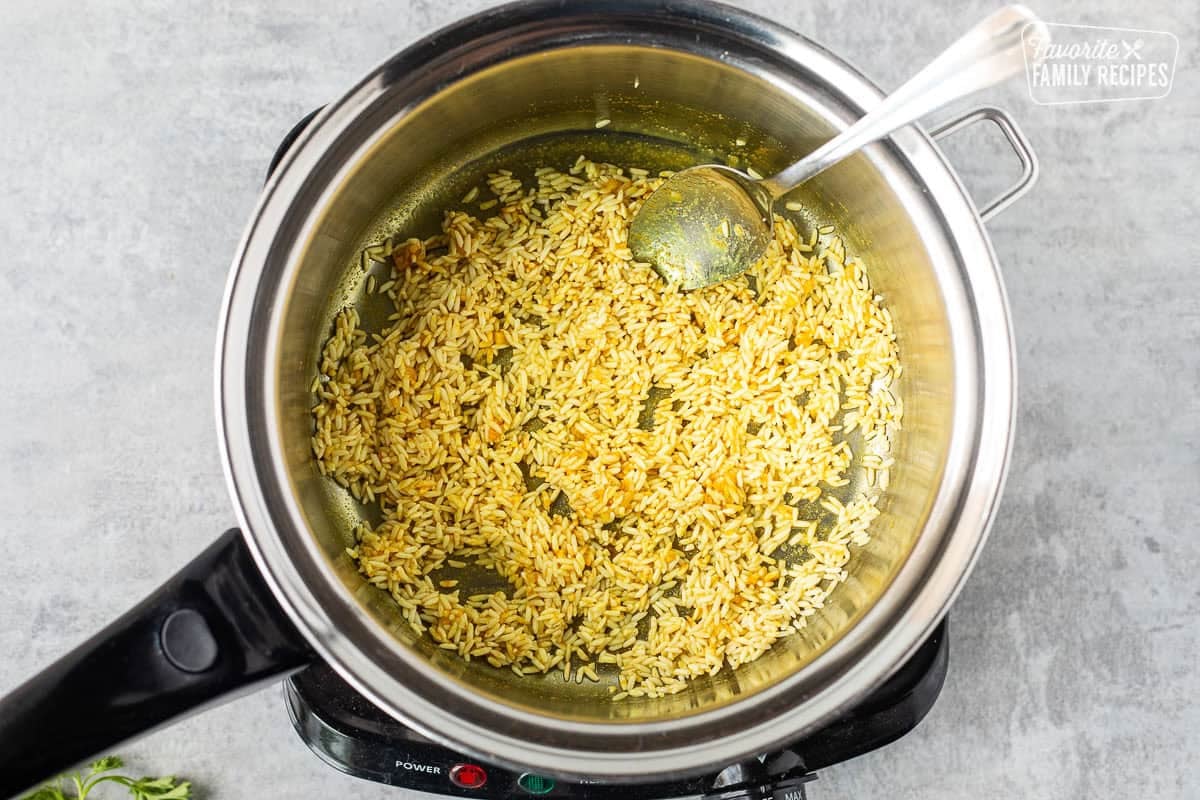 Browning rice with spices in saucepan.