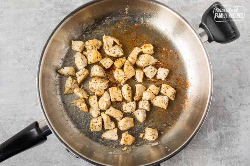 Skillet with cooked lemon pepper chicken in butter.