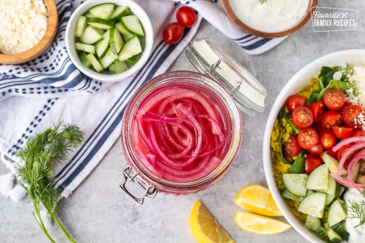 Pickled red onions in a glass container with a lid.