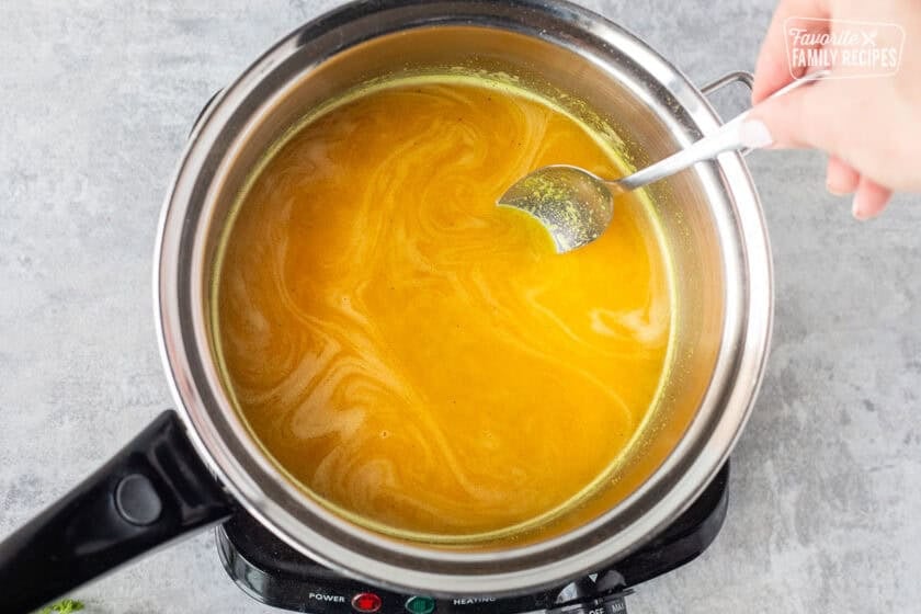 Stirring broth into rice cooked in saucepan.