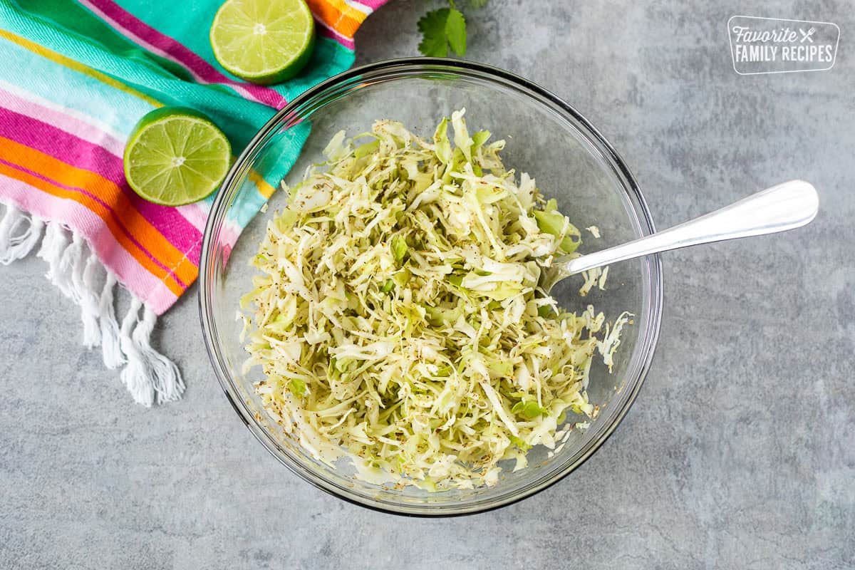 Glass bowl with cabbage, oregano and lime juice.