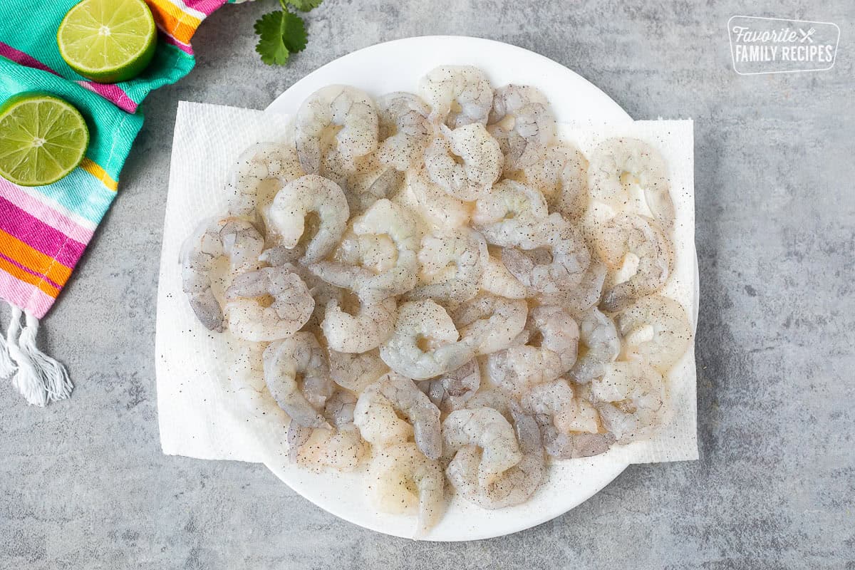 Raw shrimp on paper towels with salt and pepper.