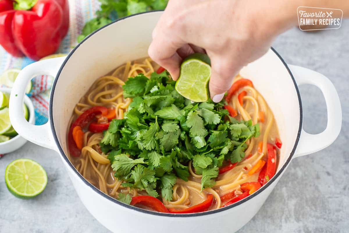 Adding fresh cilantro and squeezing lime juice into Thai peanut noodles.