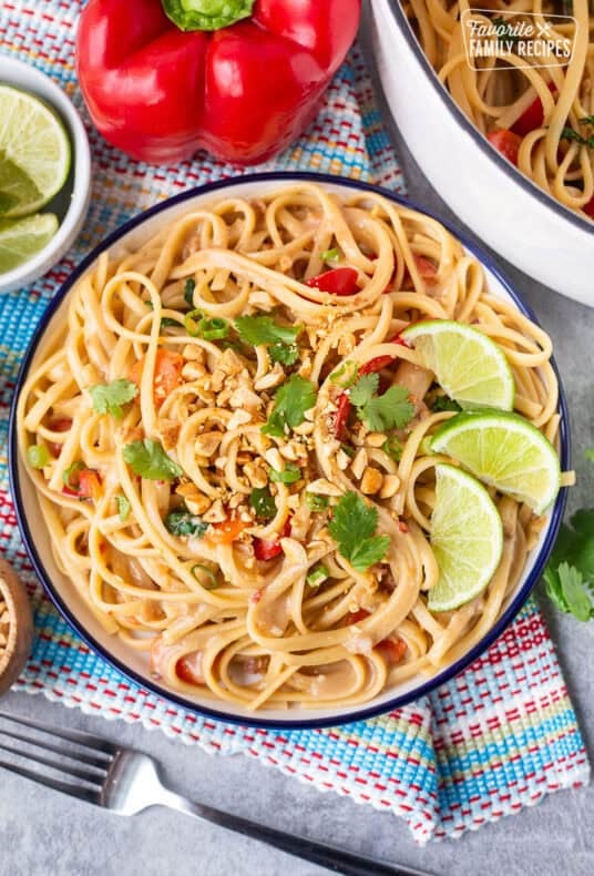 Plate of Thai Peanut Noodles with lime wedges, cilantro, and peanuts.