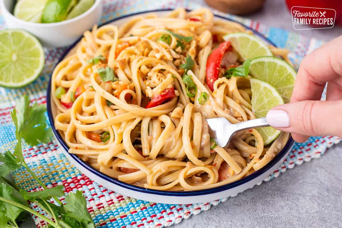 Twisting noodles with a fork on a plate of Thai Peanut Noodles.