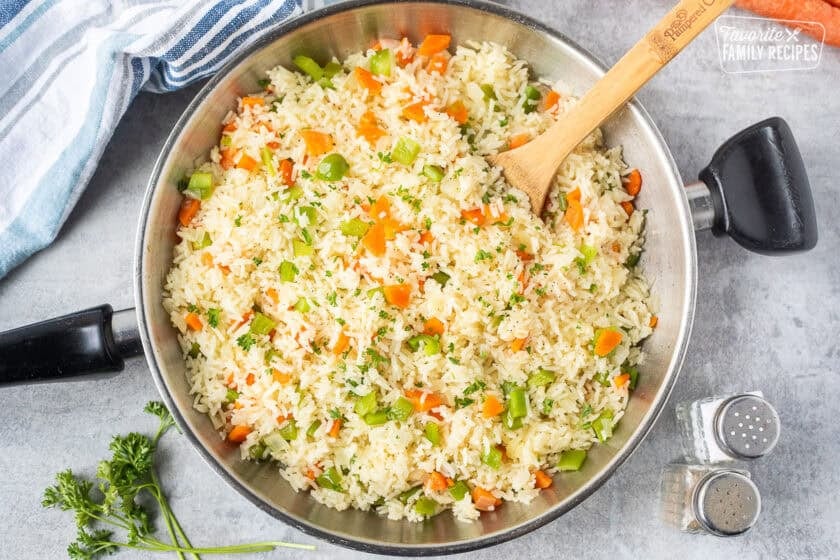 Vegetable rice in a skillet with green peppers, carrot and onion.