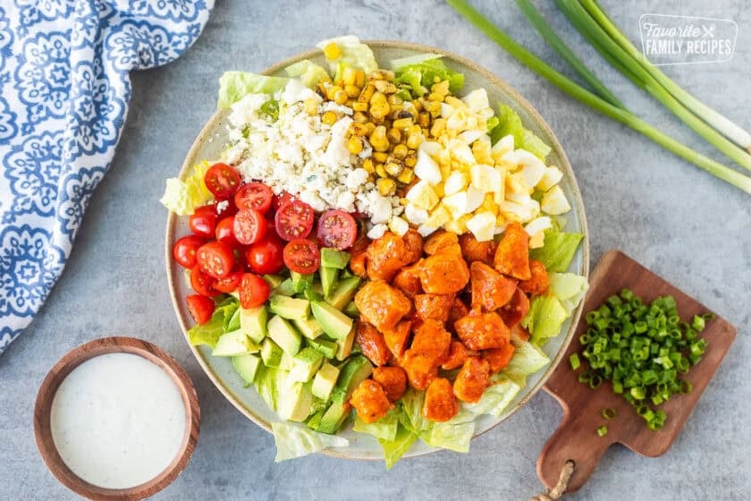 Buffalo chicken salad with lettuce, avocado, hard boiled egg, fire roasted corn, blue cheese, halved cherry tomatoes and diced chicken with Frank's red hot sauce. Ranch dressing and green onions on the side.