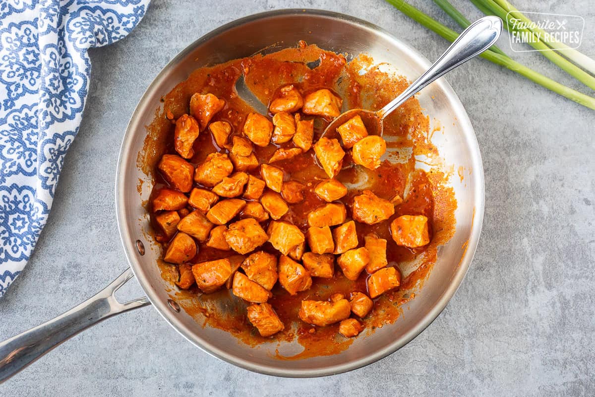 Skillet with diced chicken warmed in Frank's red hot sauce.