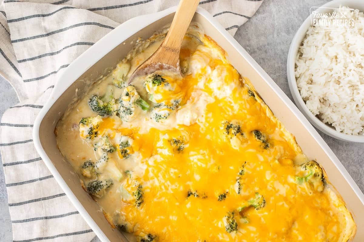 Casserole dish with chicken divan and wooden spoon. Rice on the side.