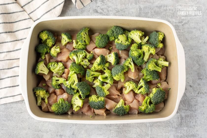 Casserole dish with diced chicken and small pieces of broccoli.