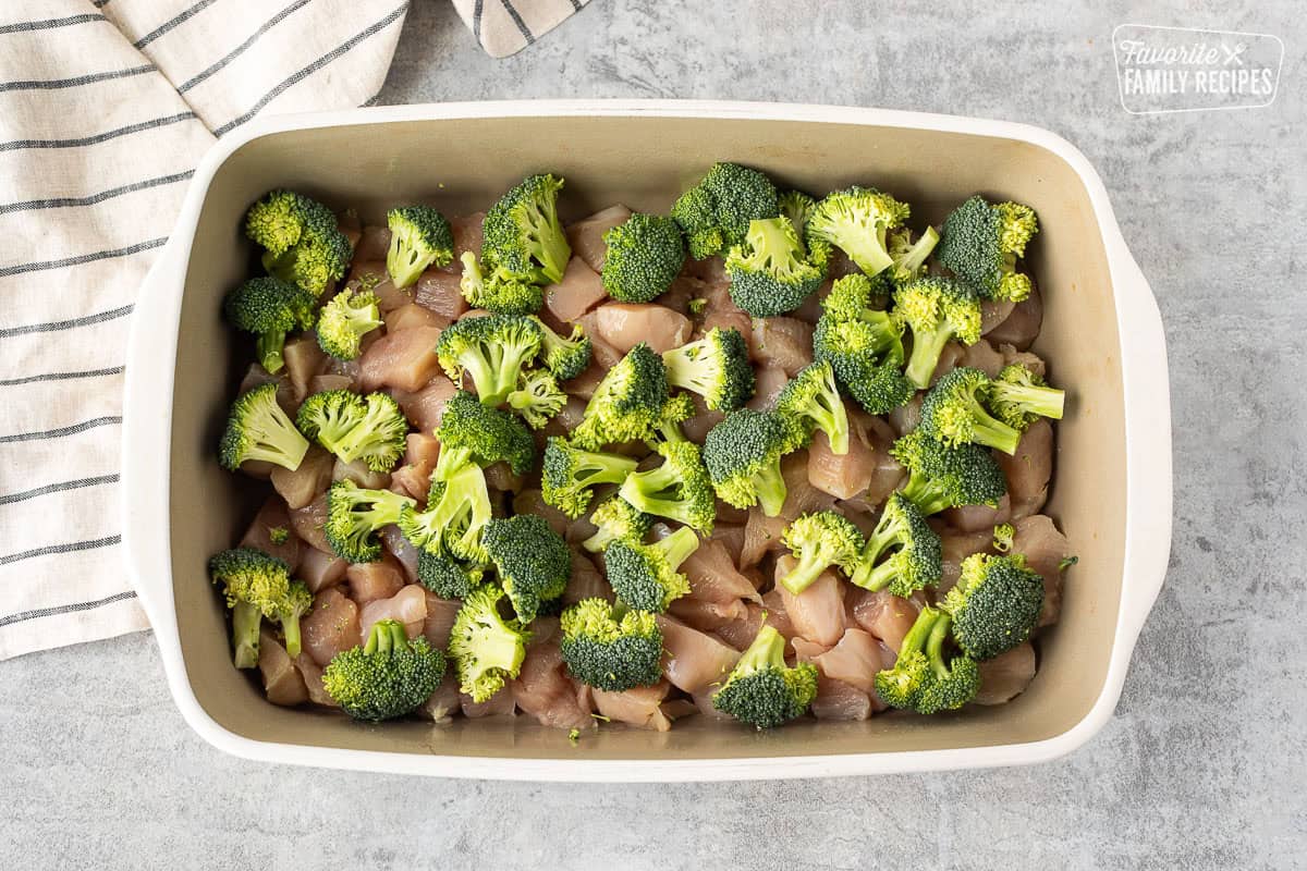 Casserole dish with diced chicken and small pieces of broccoli.