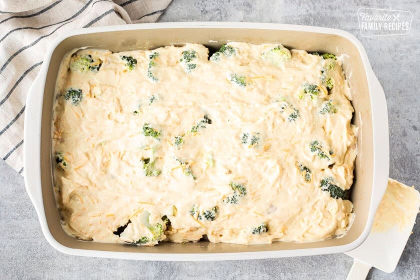Casserole dish with diced chicken, cut up broccoli, and cream of chicken mixture spread on top.