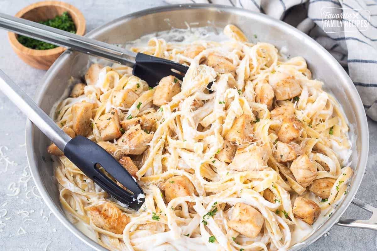 Pan of Chicken Fettuccine Alfredo with tongs.