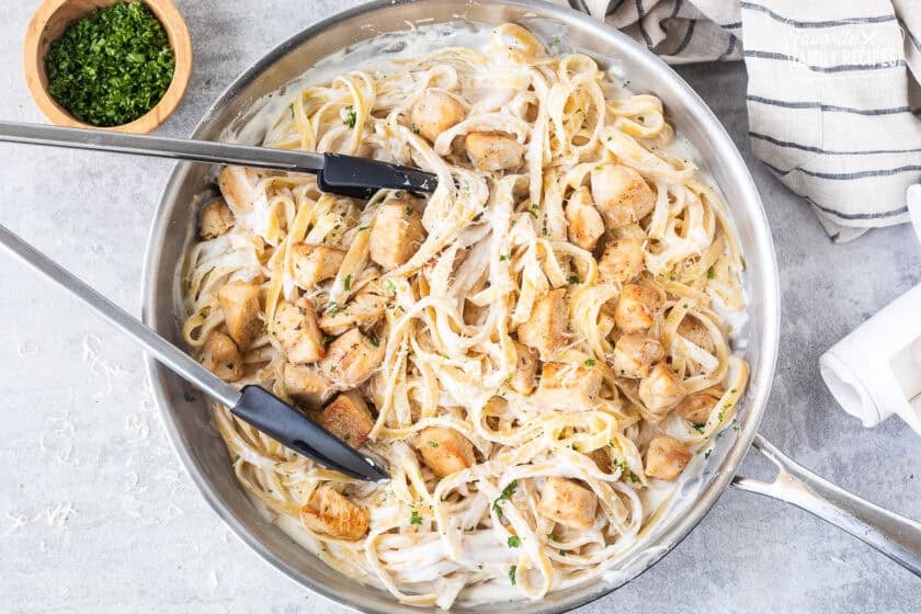 Pan of Chicken Fettuccine Alfredo with tongs.