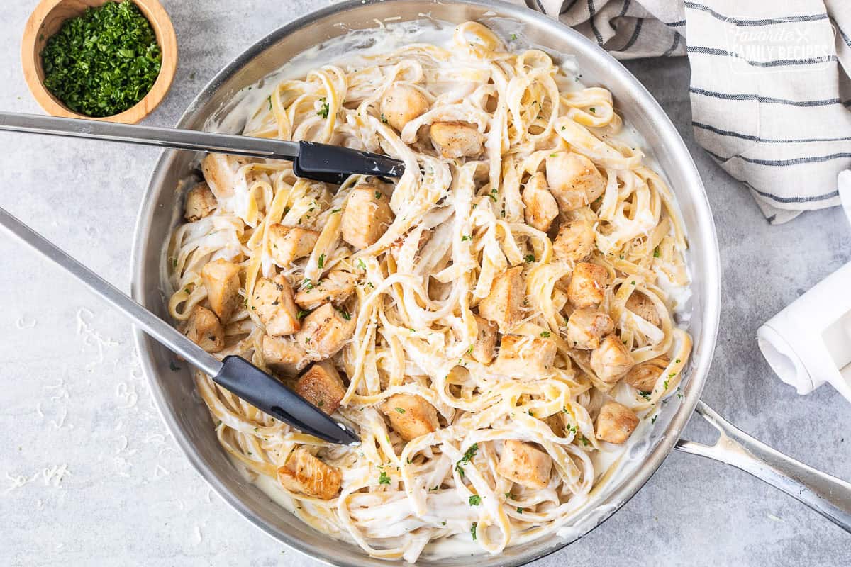 Pan of Chicken Fettuccine Alfredo with tongs.