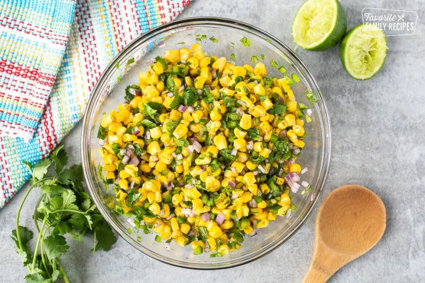 Bowl of corn salsa. Wooden spoon on the side.