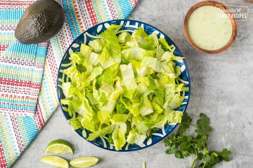 Bowl of shredded lettuce. Cilantro lime salad dressing on the side.
