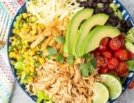 Bowl of lettuce, Mexican shredded chicken, tomatoes, black beans, corn salad, avocado, tortilla strips, cilantro and Monterey Jack cheese. Cilantro lime salad dressing on the side.