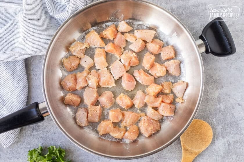 Cooking diced chicken in butter on the skillet.