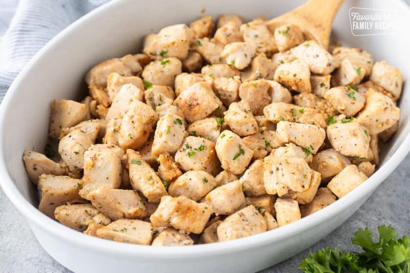 Dish of cooked diced chicken and wooden spoon.