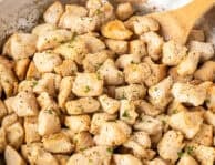 Skillet of diced chicken and wooden spoon.