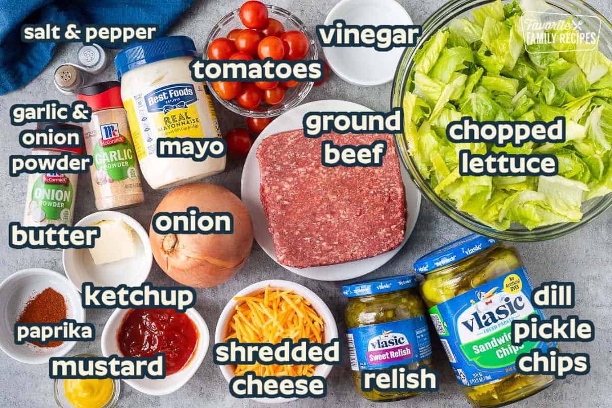 Ingredients to make burger salad including lettuce, ground beef, vinegar, cherry tomatoes, mayonnaise, garlic powder, onion powder, salt, pepper, butter, onion, cheddar cheese, dill chips, sweet relish, ketchup, paprika, and mustard.