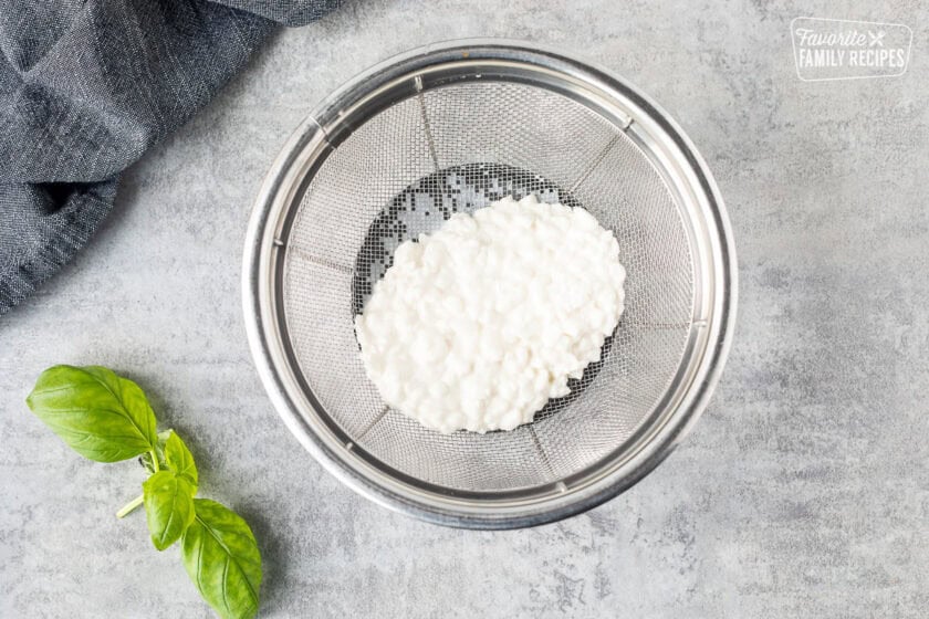 Straining cottage cheese in mesh strainer.