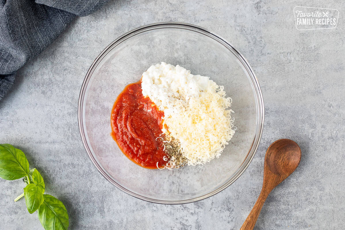 Small bowl of cottage cheese, grated parmesan cheese, basil, pizza sauce, salt and pepper.