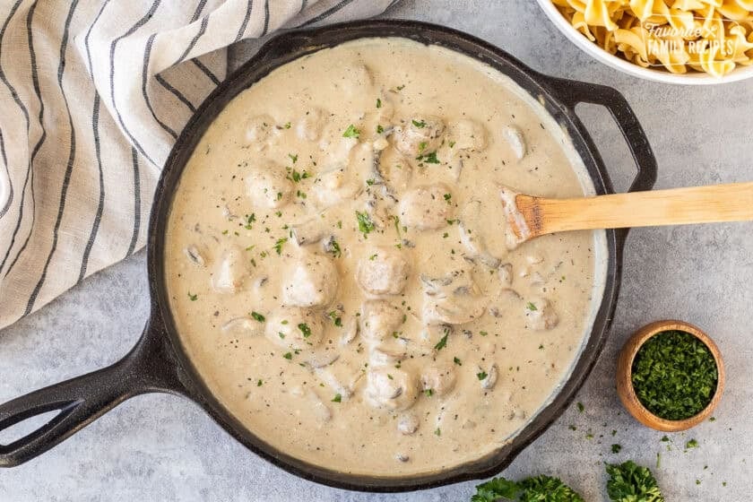 Creamy Meatball Stroganoff in a skillet with a wooden spoon.