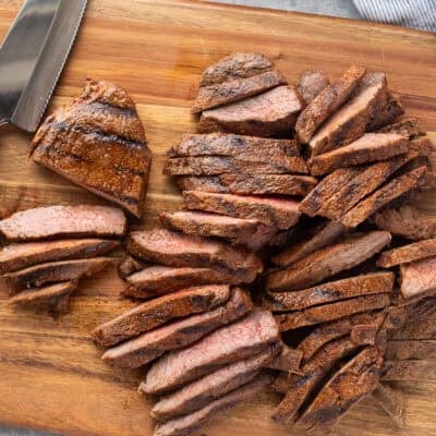 Slicing grilled steaks on a cutting board.