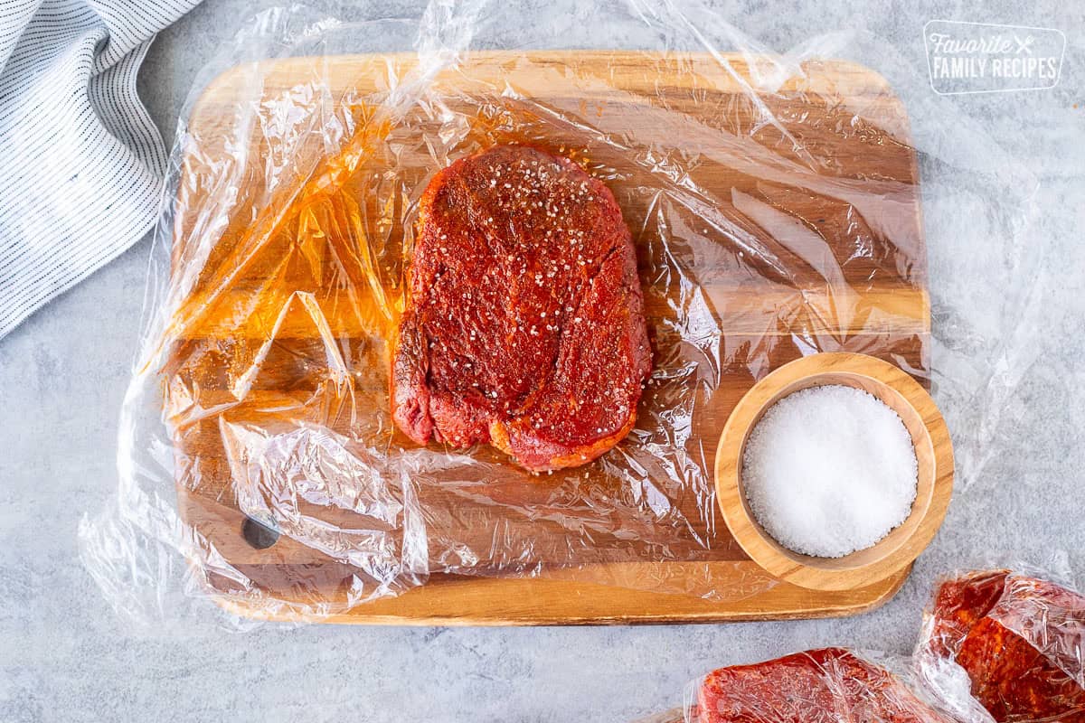 Sprinkling salt on seasoned steak.