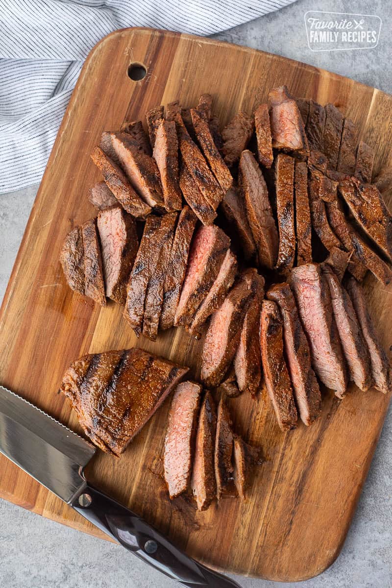 Sliced steak on a cutting board with a knife.