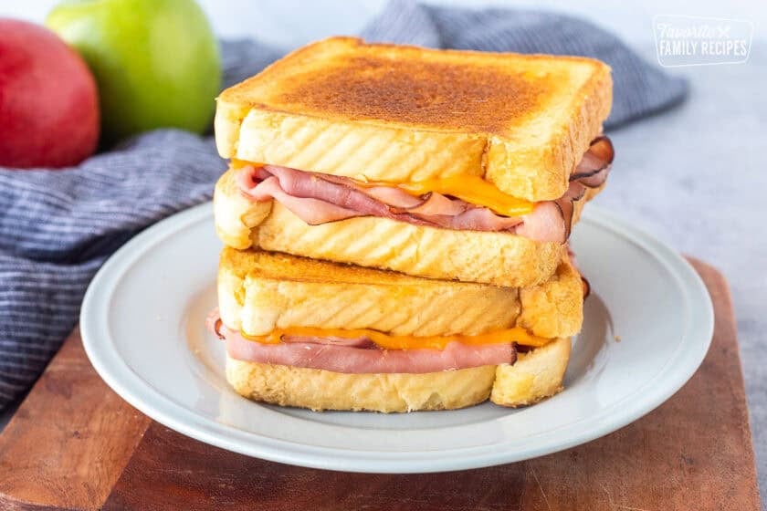 Two grilled ham and cheese stacked together on a plate.