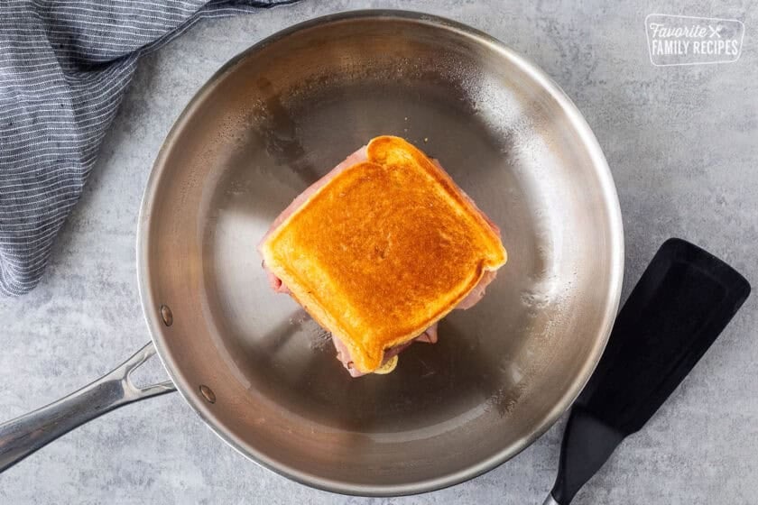 Grilled ham and cheese sandwich golden on both sides in a skillet.