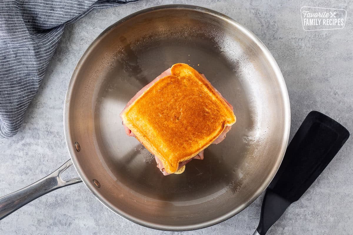 Grilled ham and cheese sandwich golden on both sides in a skillet.