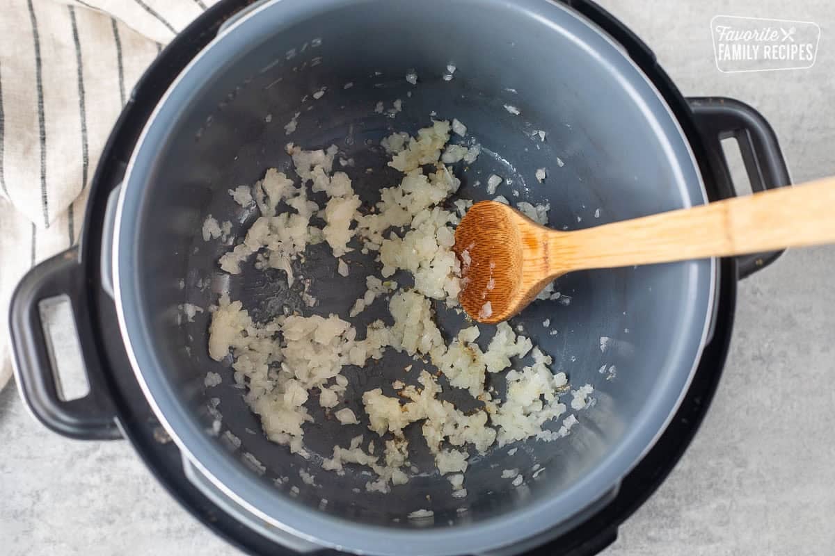 Instant pot with sautéed onions and wooden spoon.