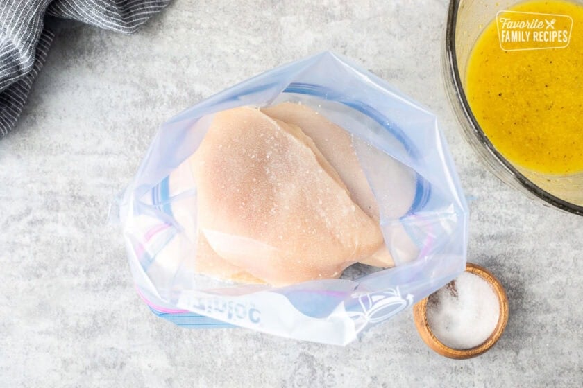 Ziplock bag with salted chicken breasts and lemon marinade on the side.