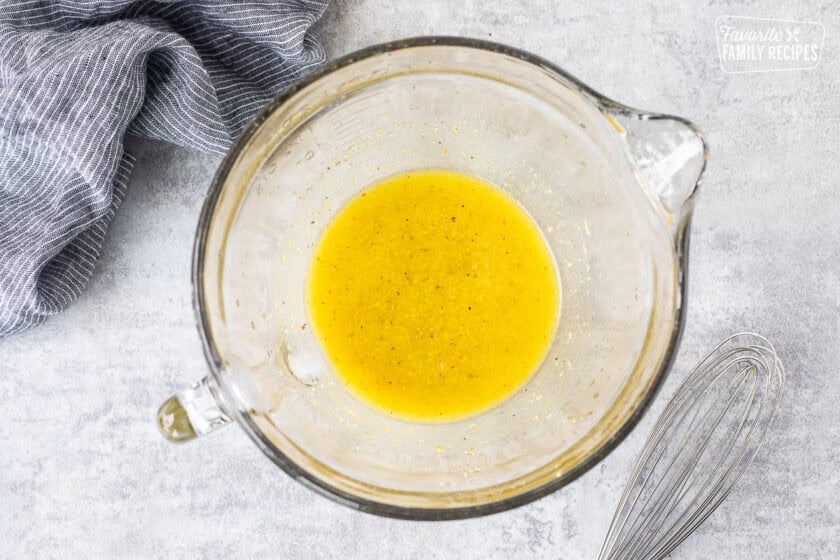 Mixing bowl with lemon garlic marinade for chicken. Whisks on the side.
