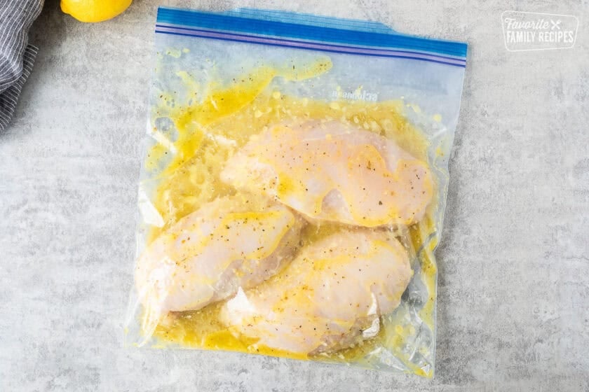 Ziplock bag with chicken breasts marinating in lemon garlic mixture.