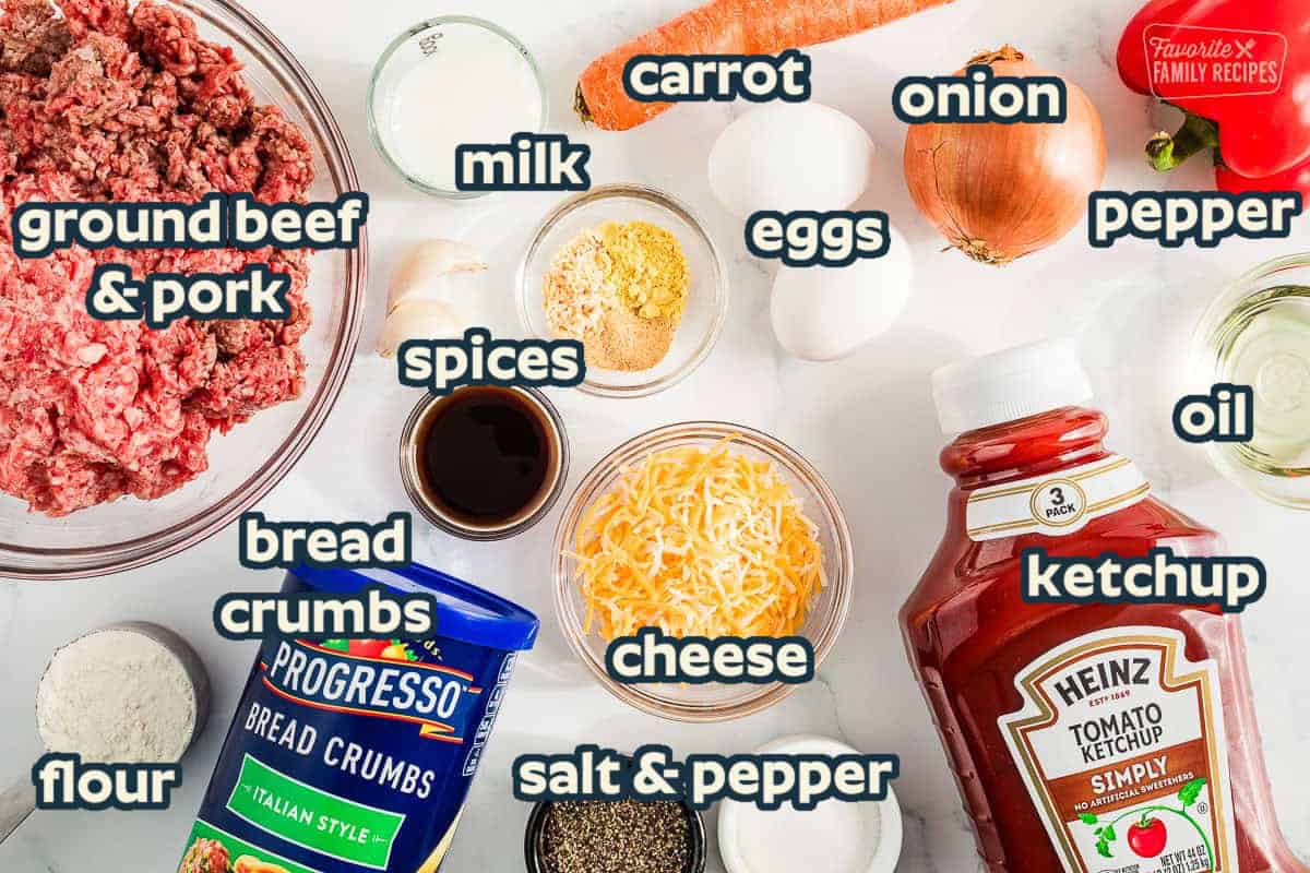 Ingredients to make meatloaf including ground beef, ketchup, cheese, seasonings, carrots, eggs, and breadcrumbs.